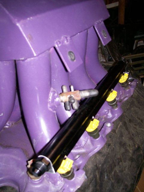 1988 Ford Bronco - Close-up of a purple intake manifold with a black fuel rail and yellow-capped fuel injectors.
