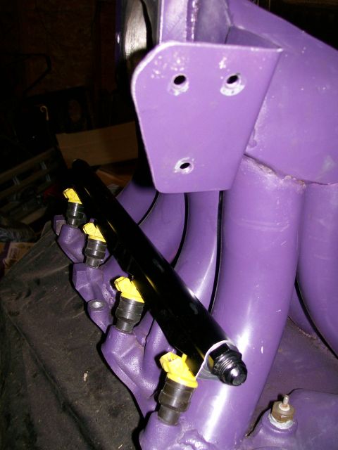 1988 Ford Bronco - Close-up of a purple intake manifold a black fuel rail with yellow injectors, likely a custom engine part.