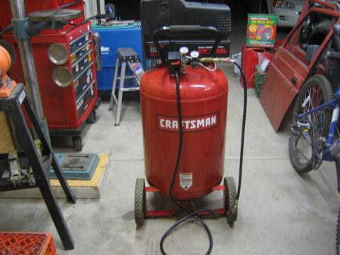1994 Ford Bronco - A red Craftsman air compressor is visible in a garage setting with tools and car parts around it.