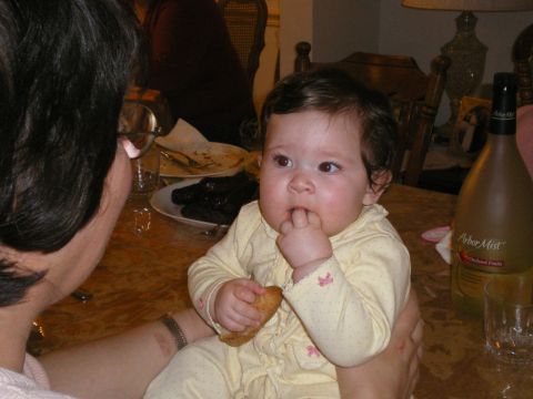 2000 Ford Crown Victoria - A baby girl sits on someone's lap, holding a cracker and looking to the side.
