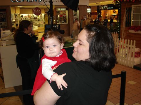 2000 Ford Crown Victoria - A woman holds a baby in a mall, with various shops visible in the background.