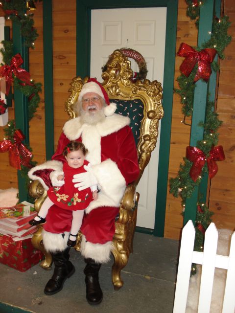 2000 Ford Crown Victoria - A baby sits on Santa's lap during a holiday event, surrounded by festive decorations.