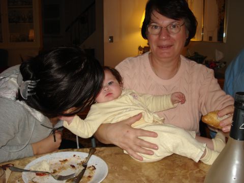 2000 Ford Crown Victoria - A woman holds a baby while another person leans in to kiss the baby. A plate of food and a bottle are on the table.