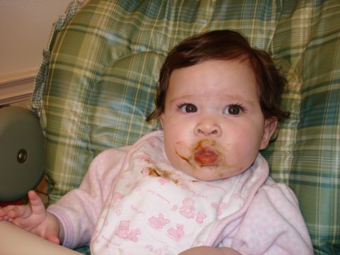 2000 Ford Crown Victoria - A baby sits in a high chair, wearing a bib and looking at the camera with a messy face.