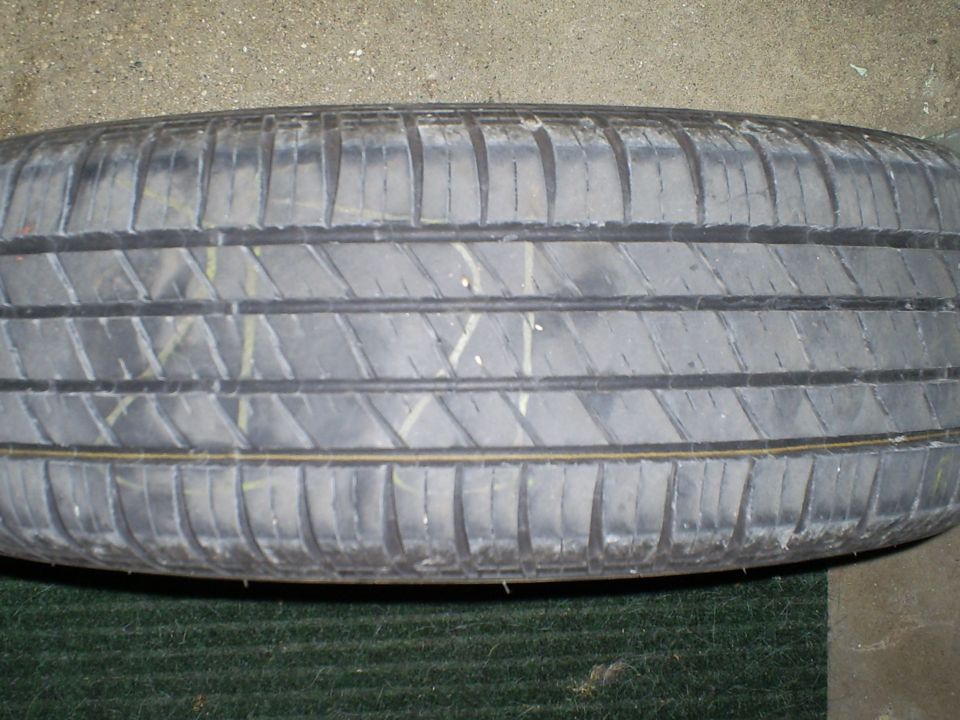 Tire tread with yellow and white markings, on a dark green surface