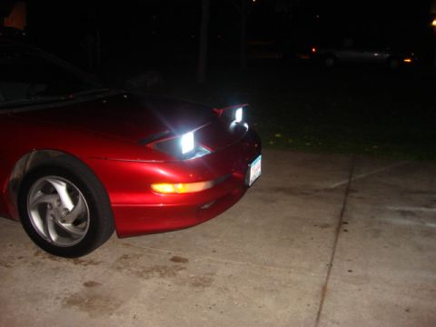 1995 Ford Probe - Front view of a red 1995 Ford Probe with its pop-up headlights on.