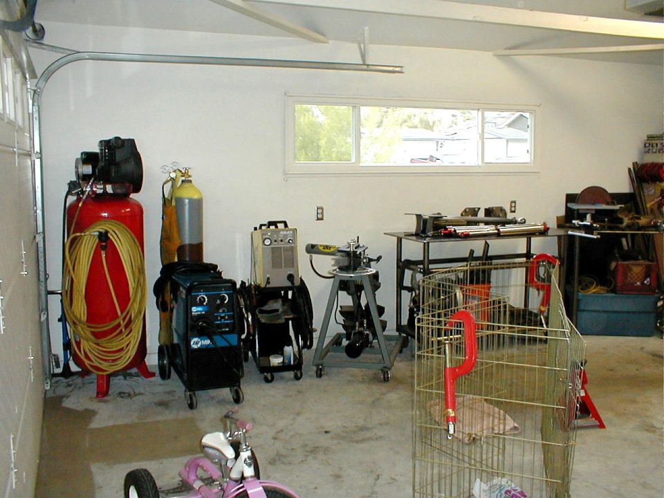 Garage workshop with air compressor, welders, pipe bender, and workbench