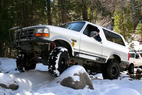 1996 Ford Bronco - 1996 Ford Bronco navigating snowy terrain with large tires and a custom bumper.