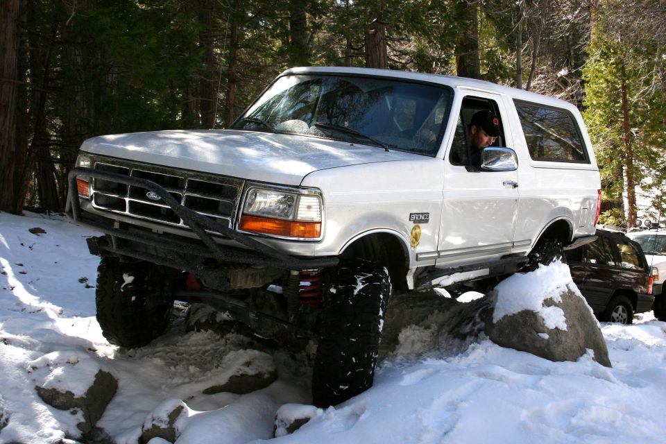 White 1996 Ford Bronco navigating rocks and snow, 3q-front view