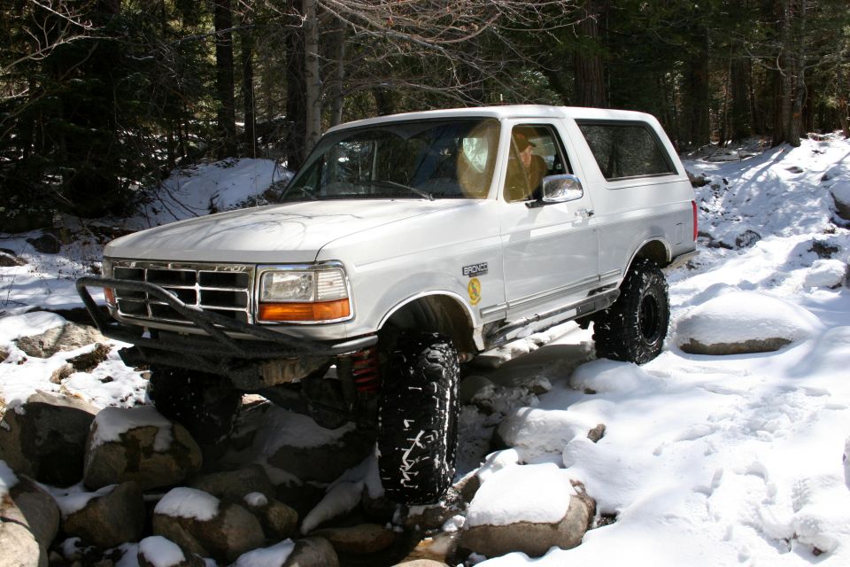 White 1996 Ford Bronco navigating a snowy, rocky trail