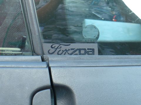 1993 Ford Probe - A close-up of a Mazda badge is affixed to the door of a gray vehicle.