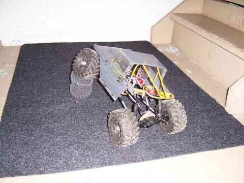 1996 Ford Bronco - A remote control rock crawler toy is positioned on a carpeted floor near a set of stairs.
