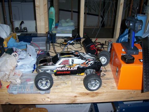 1996 Ford Bronco - A remote control monster truck sits on a workbench with various tools and electronic components.