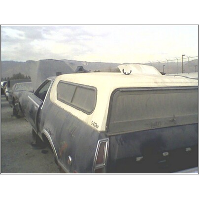 1973 Ford Ranchero - Rear view of a 1973 Ford Ranchero pickup truck with a camper shell, parked in a yard.
