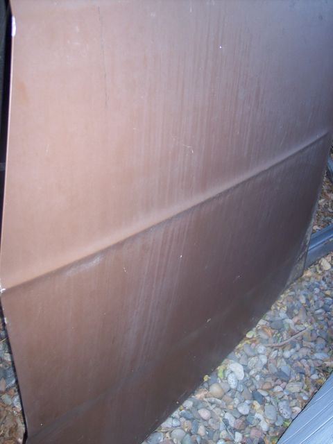 1972 Ford Ranchero - Close-up of a brown car door, showing a distinct horizontal body crease and some weathering.