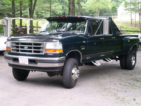 Dark green Ford F-350 dually truck with chrome grille and dual rear wheels, parked outdoors