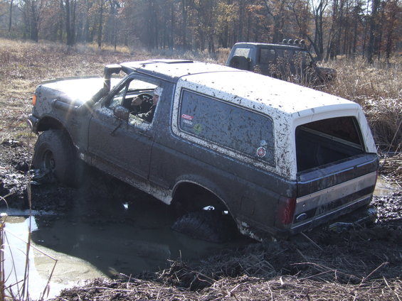 1989 Ford Bronco stuck in mud with another vehicle behind it