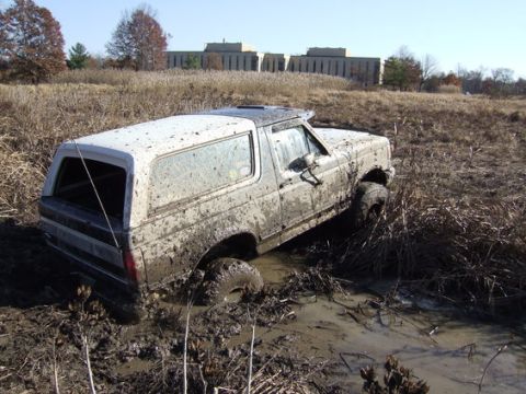 1989 Ford Bronco - This 1989 Ford Bronco is stuck deep in the mud, with only its tires and lower body visible.