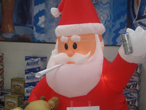 1996 Ford Bronco - An inflatable Santa Claus is holding a beer can and a white object, possibly a cigar, in front of cases of Natural Light and Extra Gold bee…