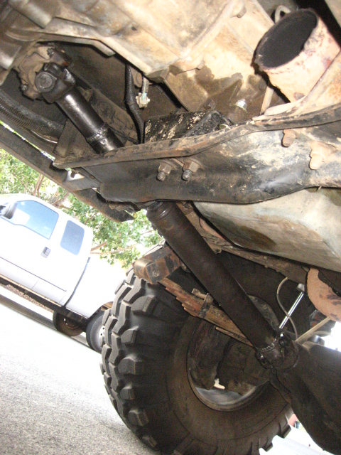 1989 Ford Bronco - The undercarriage of a modified vehicle is shown, with a driveshaft and suspension components visible.