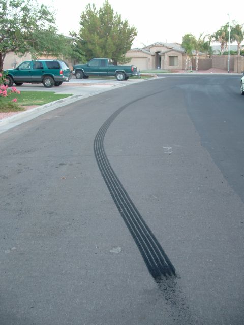 2007 Kawasaki Ninja - Tire marks are visible on the asphalt in a suburban neighborhood with parked cars and houses in the background.