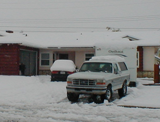Silver Ford Bronco parked in snow, towing an Outback trailer