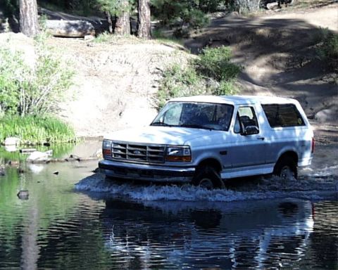 1996 Ford Bronco - White 1996 Ford Bronco fording a stream in a natural setting.