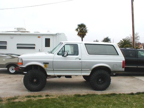 1996 Ford Bronco - Side profile of a lifted silver Ford Bronco with large off-road tires.