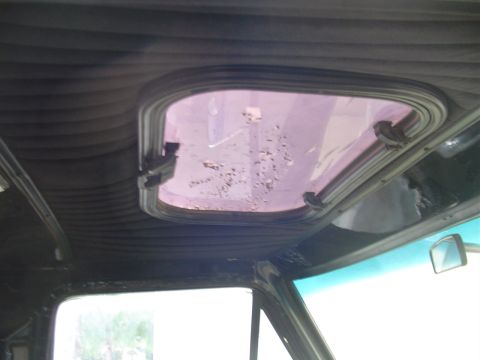 1978 Ford Bronco - Close-up of a vehicle's interior roof showing a small, damaged pop-open window.