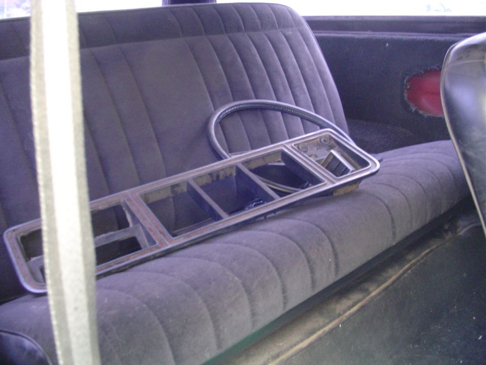 Dashboard trim piece and steering wheel rim resting on a dark upholstered seat inside a vehicle