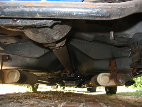 1985 Ford Crown Victoria LTD - The underside of a vehicle reveals its exhaust system, driveshaft, and fuel tank.