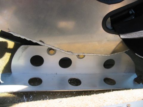 1985 Ford Crown Victoria LTD - Close-up of a metal bracket with holes, part of a vehicle's interior, with visible seatbelt and torn upholstery.