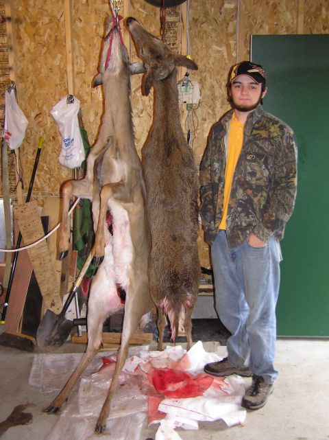 2000 Chevrolet Tahoe - Hunter poses with two deer hanging in a garage or workshop.