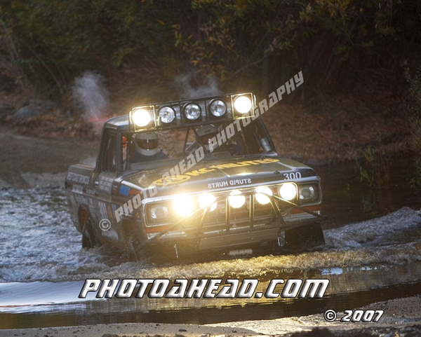 Off-road truck with bright lights driving through water