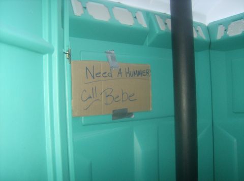 1986 Ford Bronco - Sign inside a portable toilet advertises Hummer rentals.