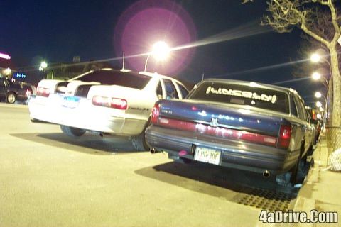 1994 Lincoln Town Car - A blue sedan is parked at night, with the word 'LINCOLN' written on its rear window.