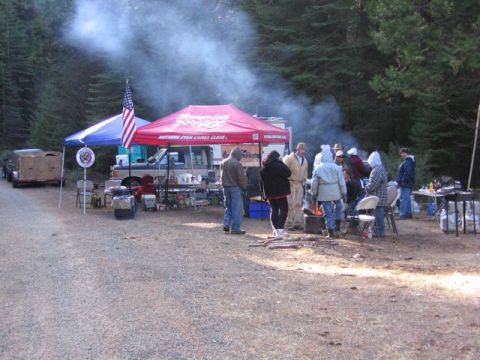 1989 Ford Bronco - People gather around a campfire and under tents in a wooded area.