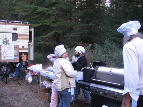 1989 Ford Bronco - People in chef hats prepare food at an outdoor gathering next to a trailer and grill.