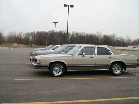 1988 Mercury Grand Marquis - Three sedans are parked in a lot on an overcast day.