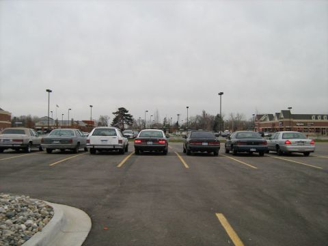 1988 Mercury Grand Marquis - A lineup of sedans, including a 1988 Mercury Grand Marquis, are parked in a lot under an overcast sky.