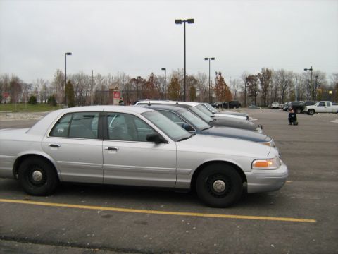 1988 Mercury Grand Marquis - Several sedans are lined up in a parking lot under an overcast sky.