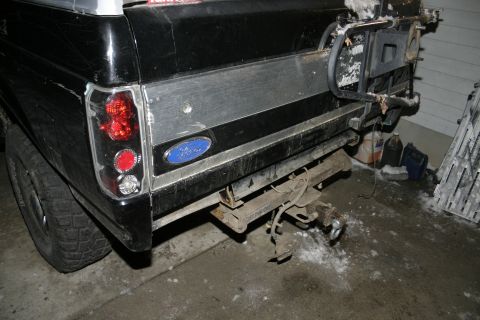 1994 Ford Bronco - The rear of a black Ford Bronco shows a tow hitch and a spare tire carrier mounted on the tailgate.