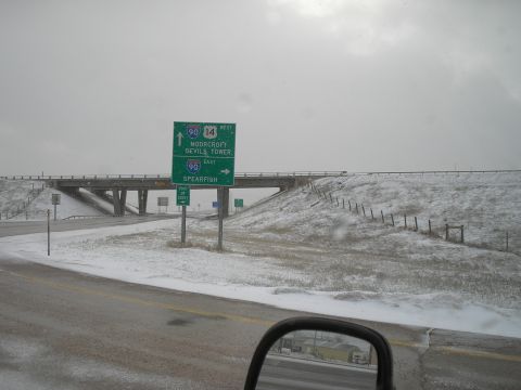 1989 Ford F-250 - A highway scene with snow-covered ground and overhead signs indicating directions to Moorcroft, Devils Tower, and Spearfish.