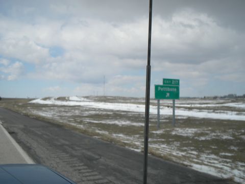 1989 Ford F-250 - A highway scene with patches of snow on the ground and a green road sign indicating Exit 217 Pettibone.