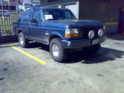 1995 Ford F-150 - Dark blue OBS Ford Bronco two-door SUV with a removable hardtop, photographed from the front three-quarter angle at a Bridgestone/Firestone…