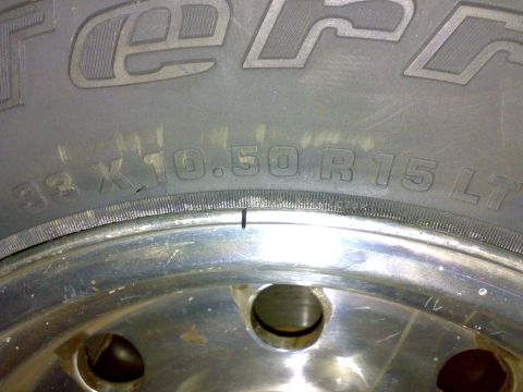 1995 Ford F-150 - Tight close-up of a tire sidewall reading "33 x 10.50 R15 LT" under raised lettering ending in "-Terr", mounted on a polished aluminum whee…