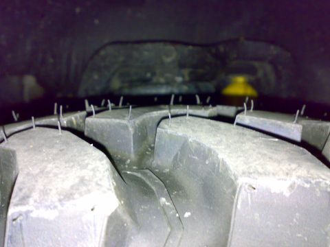 1995 Ford F-150 - Extreme close-up of the tread of a new aggressive mud-terrain tire, showing large blocky lugs still wearing their molding vent nubs and rel…