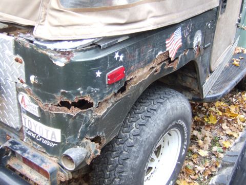 1976 Toyota Land Cruiser - This heavily rusted rear quarter panel is from a dark green SUV with a soft top, a 'TOYOTA Land Cruiser' badge.