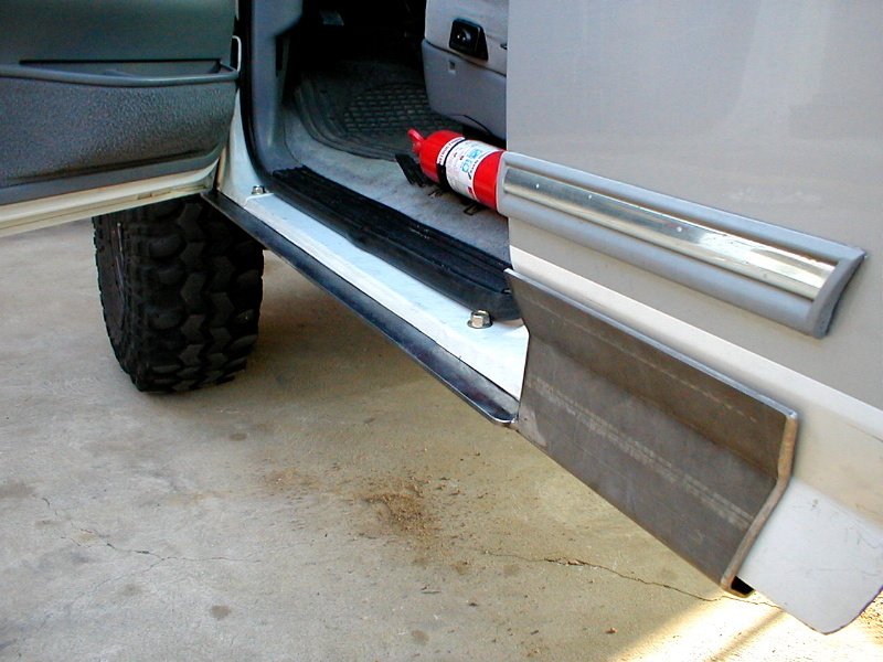 1996 Ford Bronco interior showing driver's side door open, fire extinguisher on floor, and custom metal rocker panel