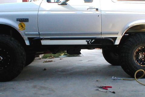1996 Ford Bronco - A white 1996 Ford Bronco is viewed from the side, with tools and a hose on the ground nearby.